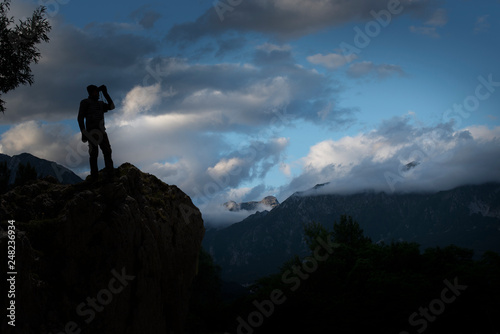 silhouette of a man watching with binoculars in the high mountains