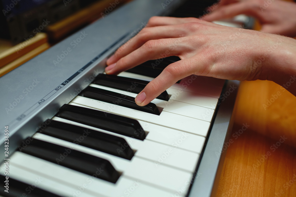 Hands of a man playing the piano in the studio.