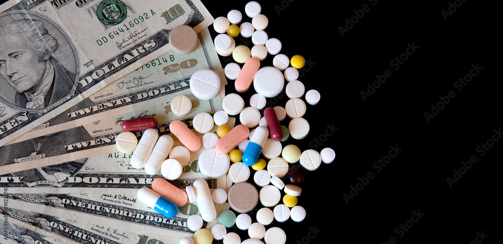 Pills on dollar money isolated on black background. Medicine expenses. High costs of medication concept Pills on dollar money isolated on black background. Medicine expenses. High costs of medication concept
