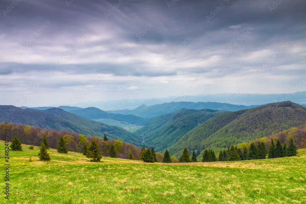 Spring landscape with grassy meadows and the mountain peaks. View from Klak Hill on Lucanska Mala Fatra mountain, Slovakia, Europe.