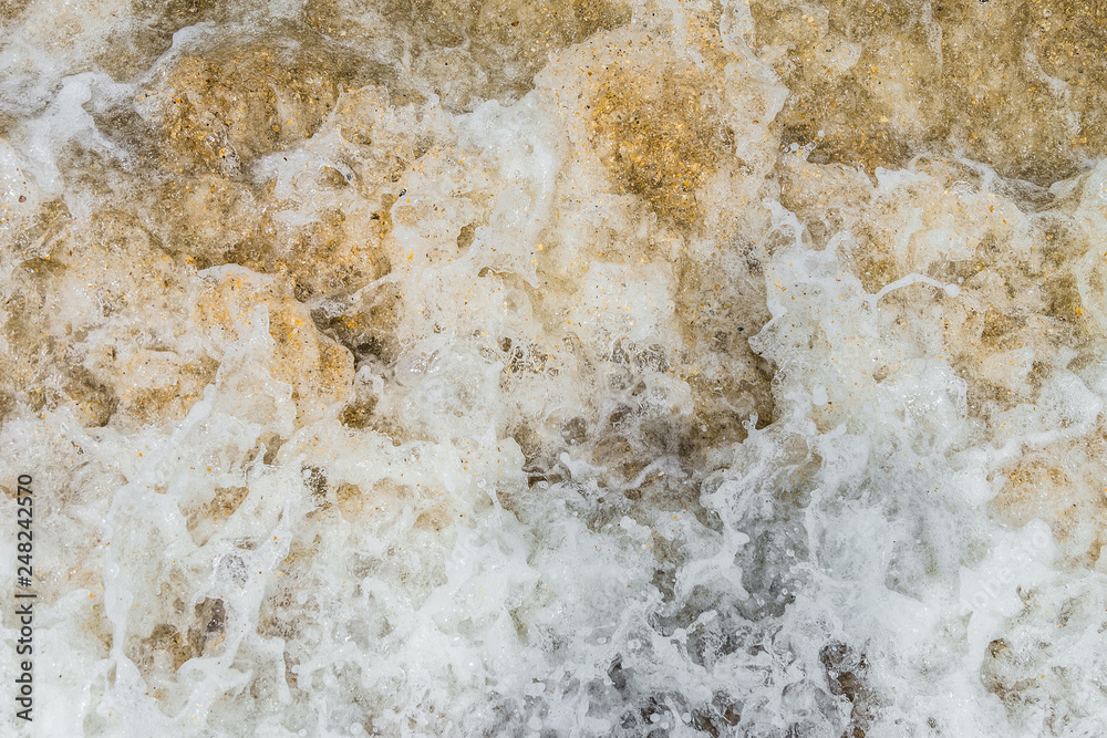 Raging sea surf close-up. Abstract background. Sea foam on the sandy shore. Raging sea surf close-up. Abstract background. Sea foam on the sandy shore.