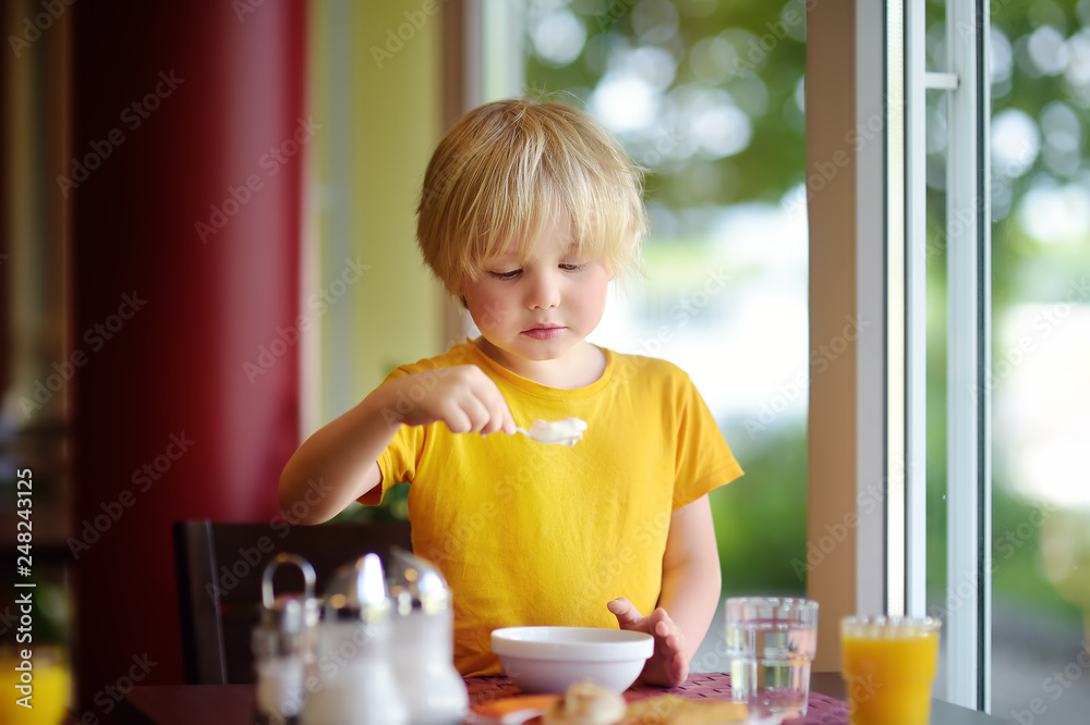Little boy eating healthy breakfast in hotel restaurant. Tasty meal in home.