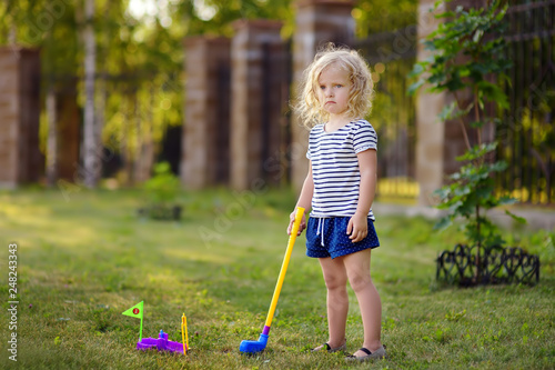 Little girl playing mini golf in spring park. Frustrated child, failure, missed. photo