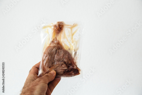 Fototapeta Naklejka Na Ścianę i Meble -  Man hand holding in hand against white background a duck leg preserved in plastic bag