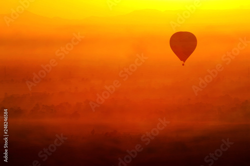 hot air balloon in the sky in Luxor, Egypt. In a beautiful sunrise with foggy orange background.