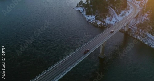 Car on a bridge, C4k aerial, rising, drone shot, following a vehicle driving on a road connecting islands, in finnish archipelago, at sunset, on a autumn evening, Varsinais-Suomi, Finland photo