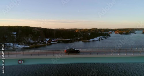 Car on a bridge, C4k aerial, tracking, drone shot, following a vehicle driving on a road connecting kasnas and kemionsaari, in the finnish archipelago, on a sunny, autumn evening, Finland photo