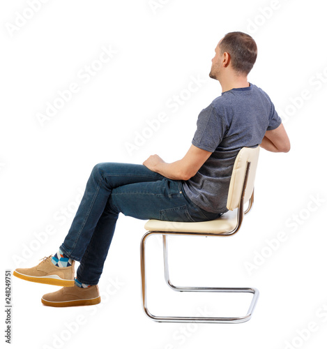 Side view of a man sitting on a chair.