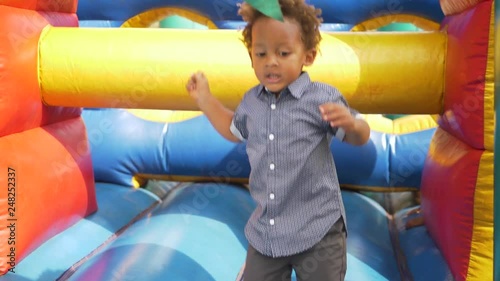 A tight super slow motion shot of a mixed raced child jumping on a bouncing castle. photo