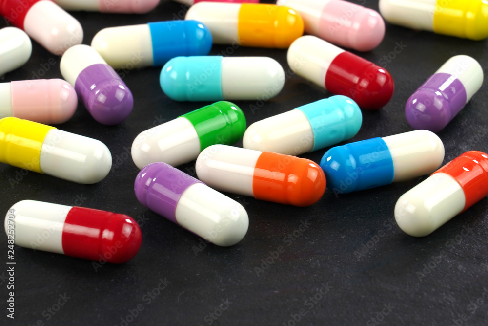 Colorful medical capsules on black background . Macro image. Colorful medical capsules on black background . Macro image.