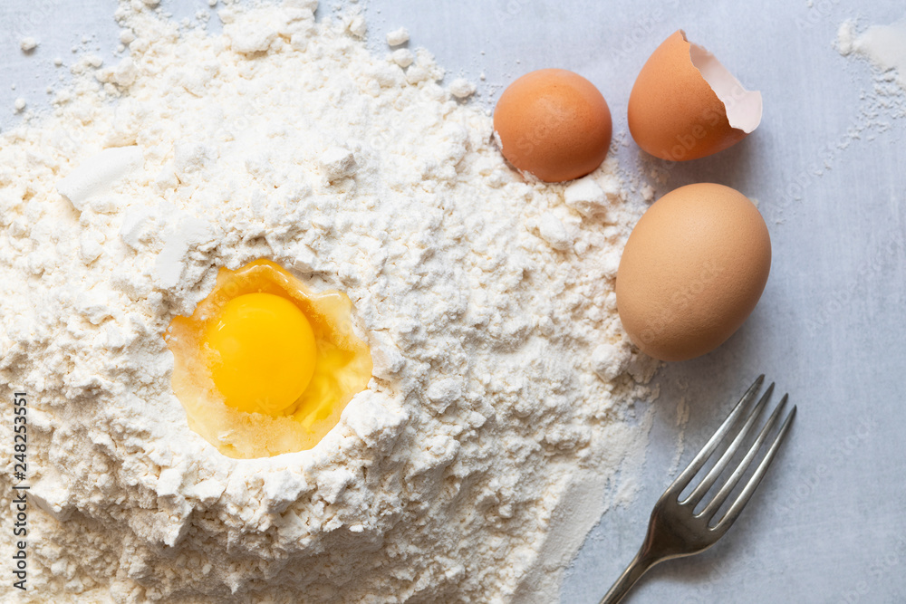A raw egg in flour with a fork. A raw egg in flour with a fork.