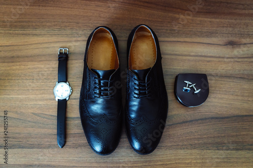 Men s leather shoes  watches and cufflinks on the background of a brown table. Clothing accessories businessman. Concept of grooms accessories at wedding day.