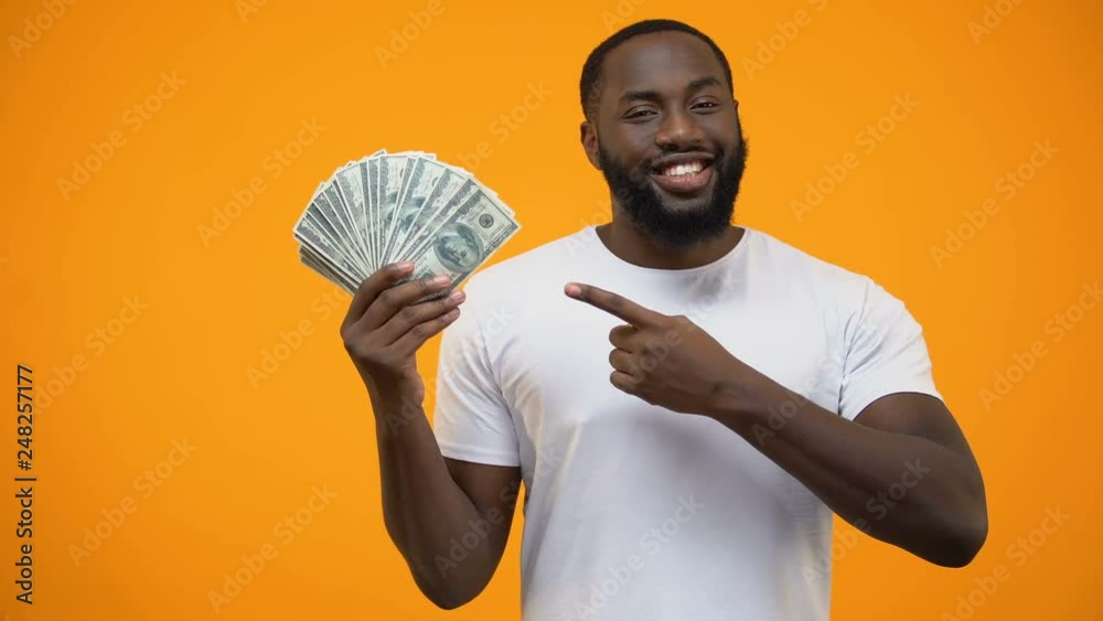 African-American man pointing finger into bunch of dollars, capital investment