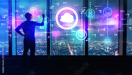Cloud computing with man writing on large windows high above a sprawling city at night © Tierney