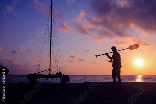 Silhouette asian man with paddle and sailing catamaran on the beach © THANAGON