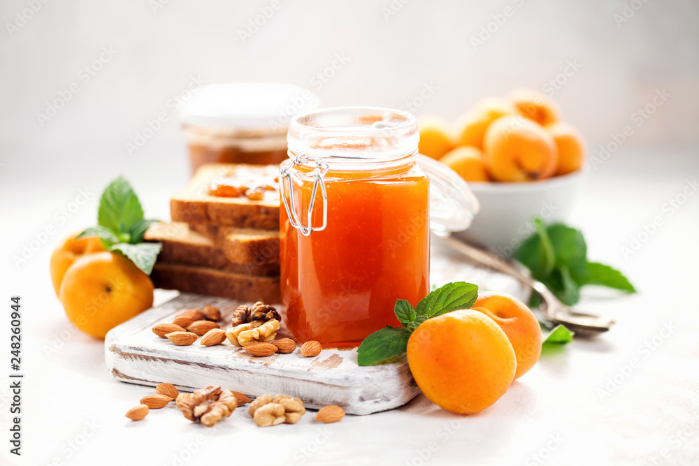 Apricot jam in a jar and fresh fruits with nuts on wooden cutting board. Healthy breakfast Apricot jam in a jar and fresh fruits with nuts on wooden cutting board. Healthy breakfast