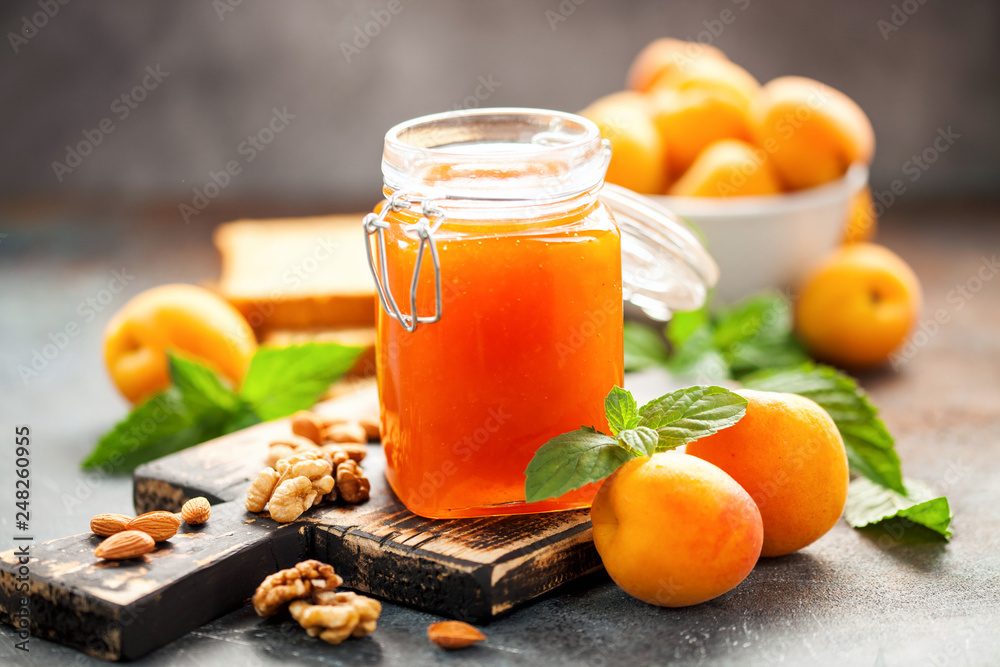 Apricot jam in a jar and fresh fruits with nuts on wooden cutting board. Healthy breakfast Apricot jam in a jar and fresh fruits with nuts on wooden cutting board. Healthy breakfast