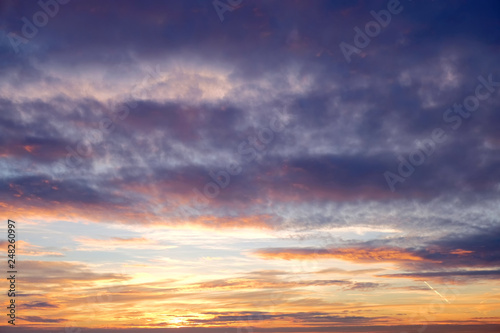 sunset sky and sun light through clouds on beautiful evening time with heaven natural calm dusk colors and sunrise red orange dawn mood nature weather outdoor landscape background © vaalaa