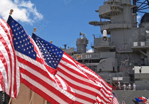 Valokuva US flags flying beside the Battleship Missouri in Pearl Harbor, Honolulu, Oahu, Hawaii with 4 sailors walking on deck