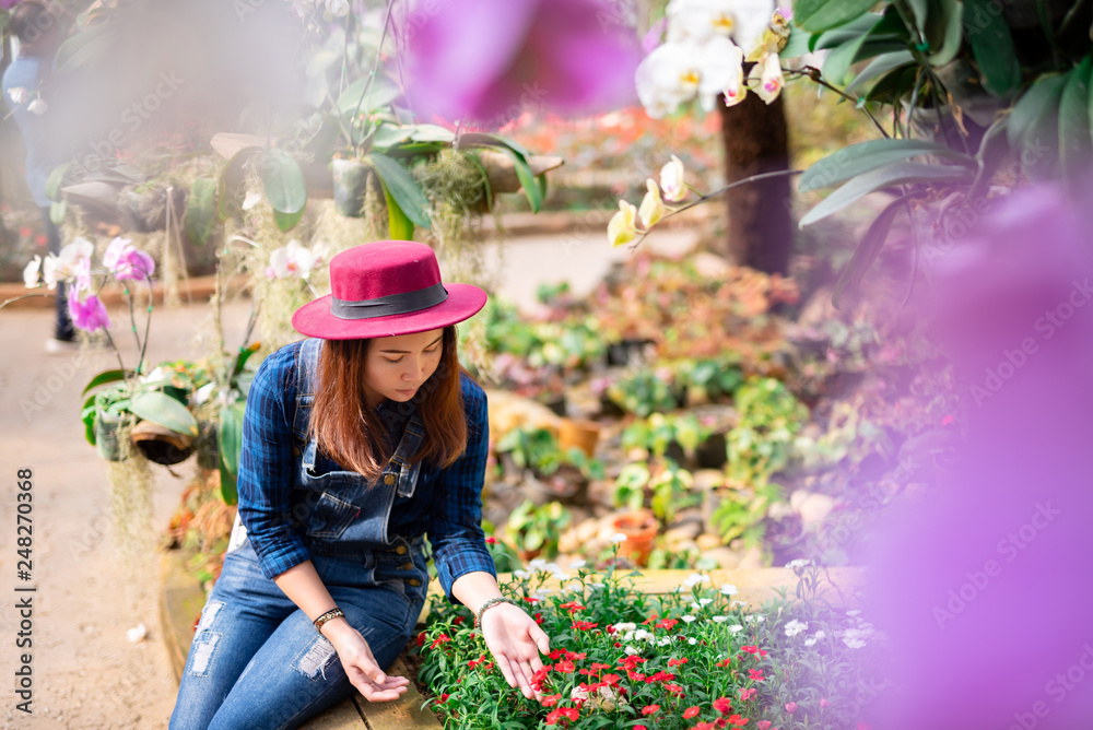 Young women and flower care in the garden that are blooming in the morning