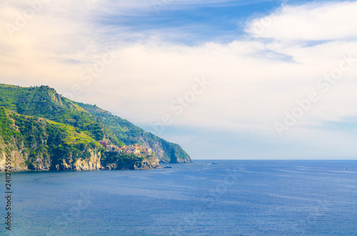 Aerial top panoramic view of Manarola village on cliff and Gulf of Genoa, Ligurian Sea, coastline of Riviera di Levante, National park Cinque Terre, blue sky copy space, La Spezia, Liguria, Italy © Aliaksandr