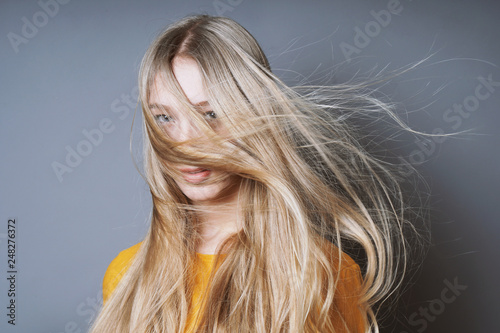 Slika na platnu blond young woman with long windswept tousled hair blowing into her face