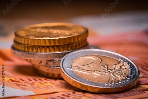 Two euro coins over euro banknotesCoins on a blurred background coin denomination of two euros. Currency of the European Union. photo