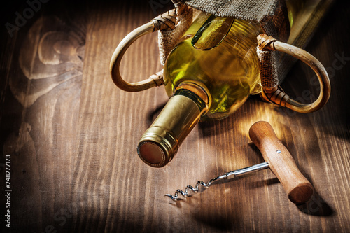 bottle of white wine in burlap bag and vintage corckscrew photo