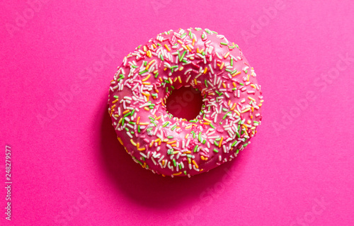 Round pink donut cake at bright fuchsia background
