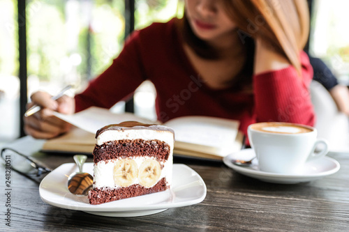 Red shirt woman writing notebook with cup of coffee and chocolate banana cake,Choco banana cake,Coffee time,Selective focus