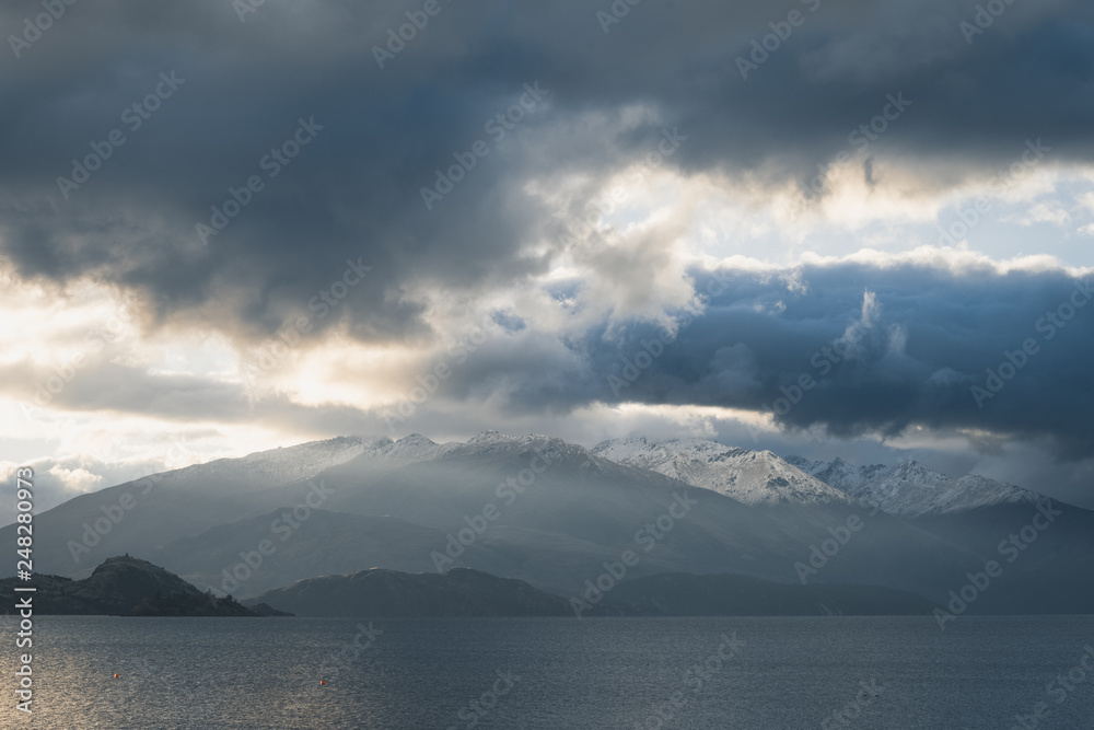 Clouds over snowy mountain and lake