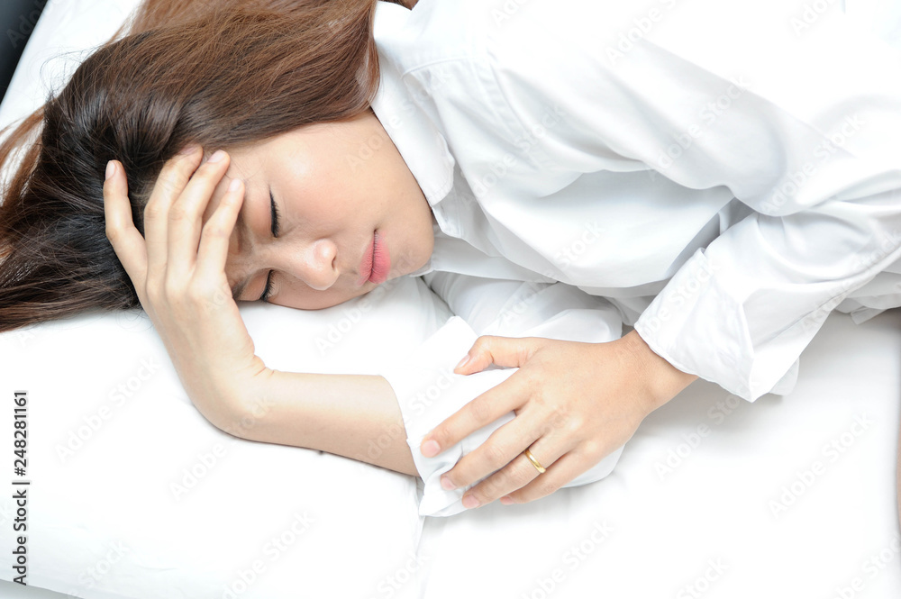 Asian woman headache on white bed,Asian women are suffering from migraines,Asian women are suffering from influenza Asian woman headache on white bed,Asian women are suffering from migraines,Asian women are suffering from influenza