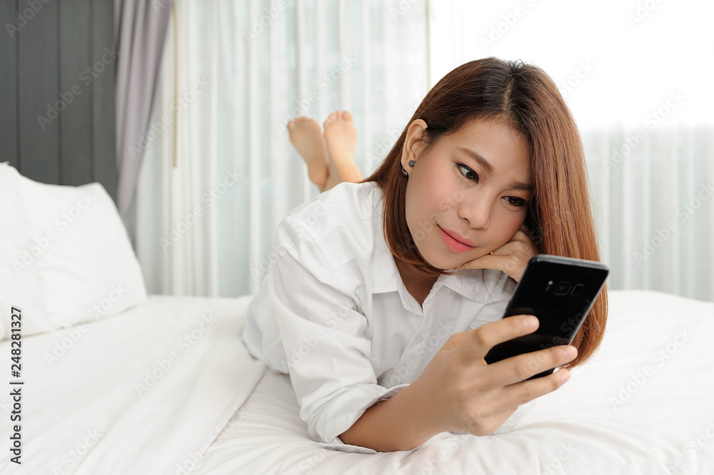 Long hair women have relax time in bedroom,Women lay on bed and using smartphone for chatting on social networ in bedroom Long hair women have relax time in bedroom,Women lay on bed and using smartphone for chatting on social networ in bedroom