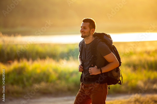 Portrait of a man tourist at sunset on the background of the river and the forest