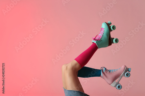 Woman with vintage roller skates on color background, closeup. Space for text