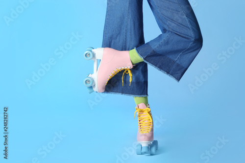 Woman with vintage roller skates on color background, closeup. Space for text