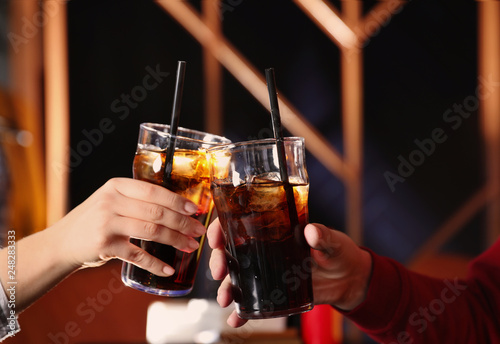 Young couple with glasses of refreshing cola indoors, closeup