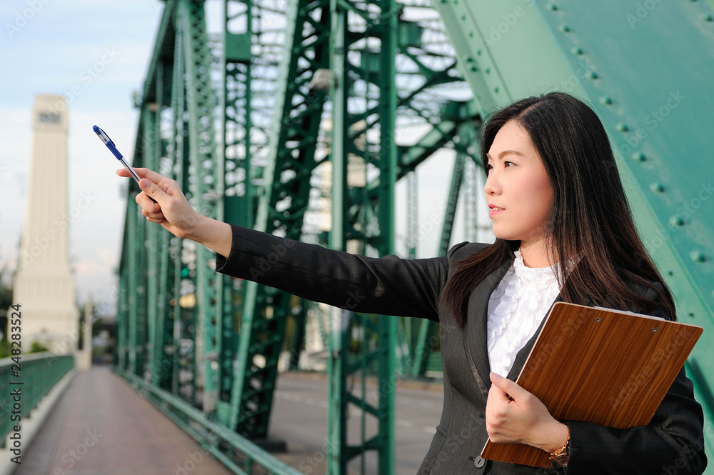 Fototapeta premium Asian business women happy and smile with her clipboard,Portrait Beautiful Asian business women,Asian business women pointing goal with pen,Selective focus
