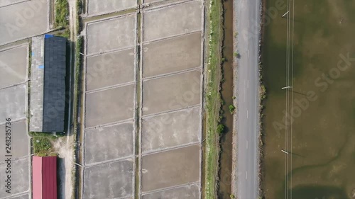 Aerial view rise vertically above geometric pattern of salt fields in Asia; camera pivots to reveal 2nd angle as it ascends. photo