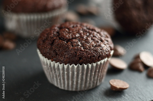 Chocolate homemade cupcakes muffins on a black background with chocolate drops in the background. Bakery style. Dark food photo