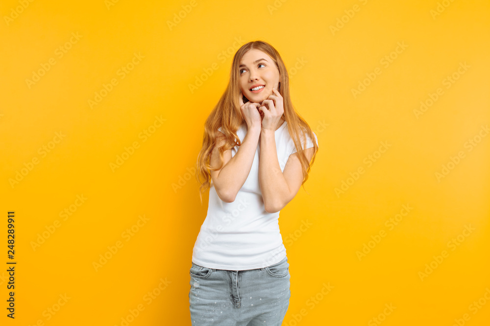 beautiful girl in white t-shirt holding hands near face, portrait of cute woman on yellow background