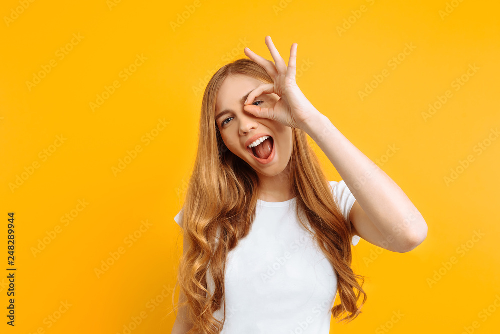 girl shows OK, on yellow background, beautiful model girl shows OK, on yellow background, beautiful model
