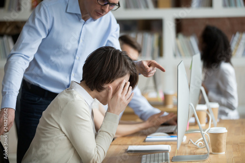 Stressed female employee suffering from discrimination of angry male boss photo