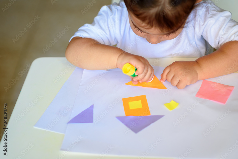 Cute little girl make applique, glues colorful house, applying a color paper using glue stick while doing arts and crafts in preschool or home. The idea for children's creativity, art project. Cute little girl make applique, glues colorful house, applying a color paper using glue stick while doing arts and crafts in preschool or home. The idea for children's creativity, art project.