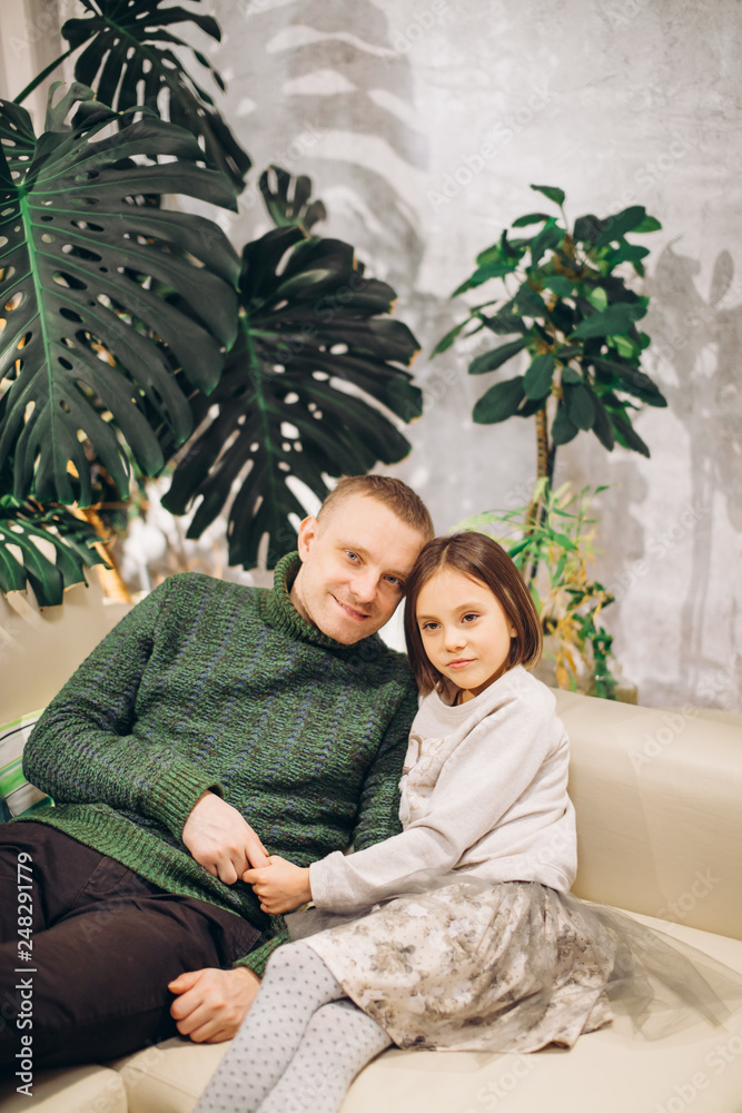 Fototapeta premium close up portrait of handsome father and his cute daughter sitting on the sofa. love, relation, fatherhood, parenthood.