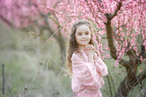 Beautiful young woman in pinkstylish garden dress blooming sakura