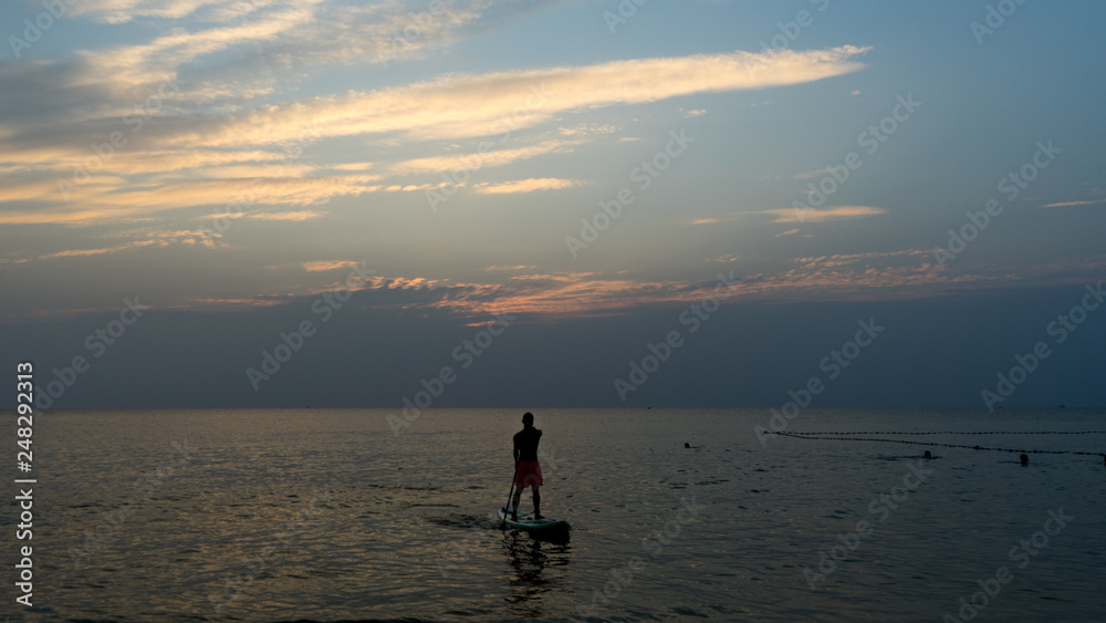 Stand up paddle board at sunset on the Phu Quoc beach Vietnam,travel concept,beach activity,Person stand up paddle boarding at dusk beautiful sunset colors