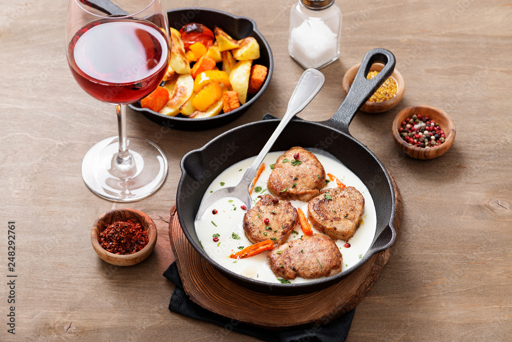 Pork meat medallions with baked potatoes and cream sauce .