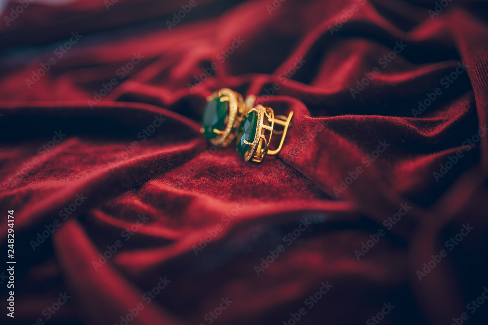 Golden jewelry with gem on the red velvet background