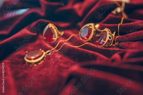 Golden jewelry with gem on the red velvet background